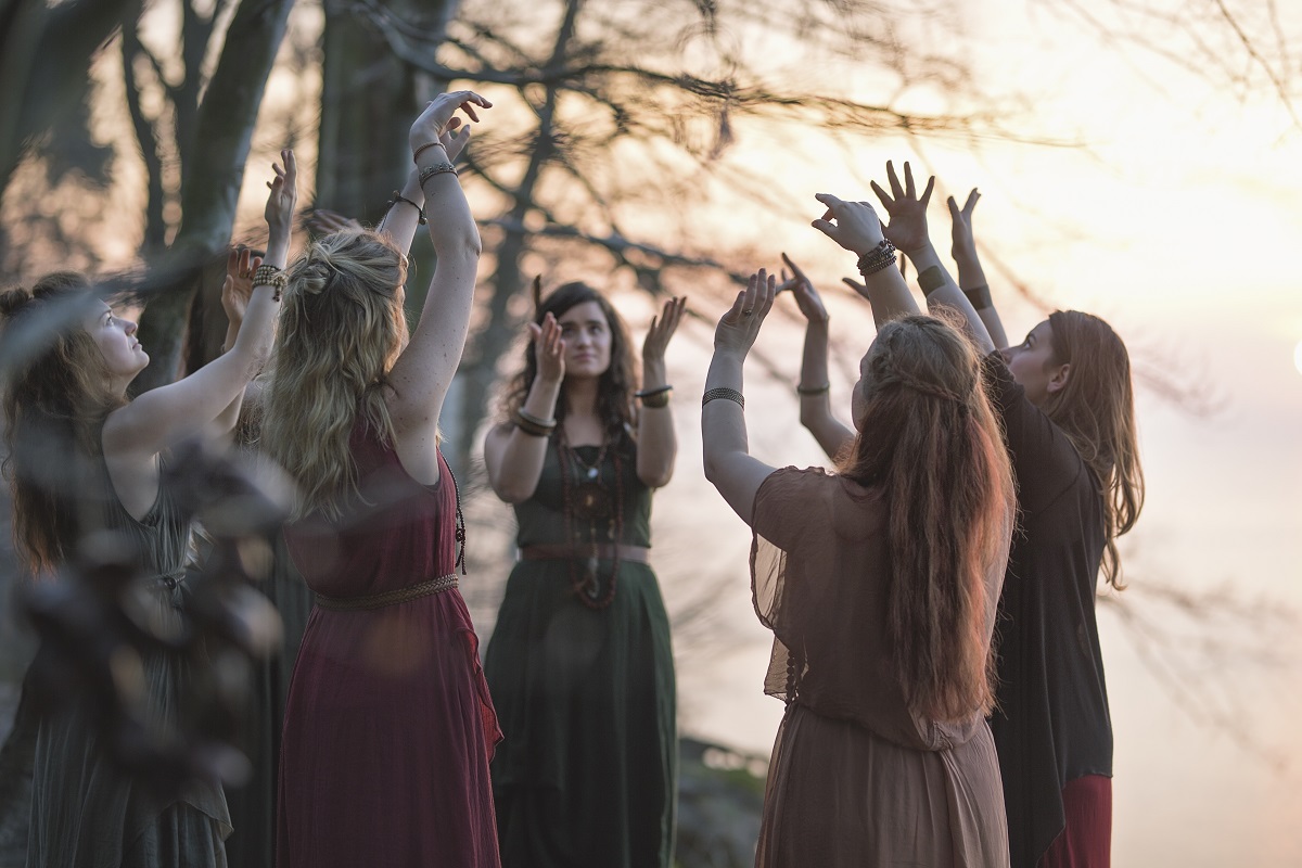 Photo of a band: seven women standing in a circle with their hands raised. - grafika artykułu