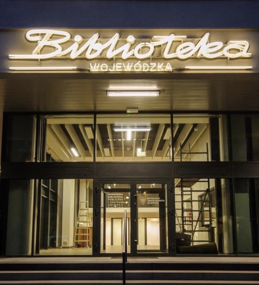 fot. materiały WBPiCAK Budynek Biblioteki Wojewódzkiej nocą. Nad wejściem jasny neon.