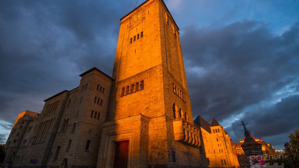 Wieża Centrum Kultury Zamek po zmierzchu, oświetlona od dołu reflektorami. Nad nią widać mocno zachmurzone niebo.