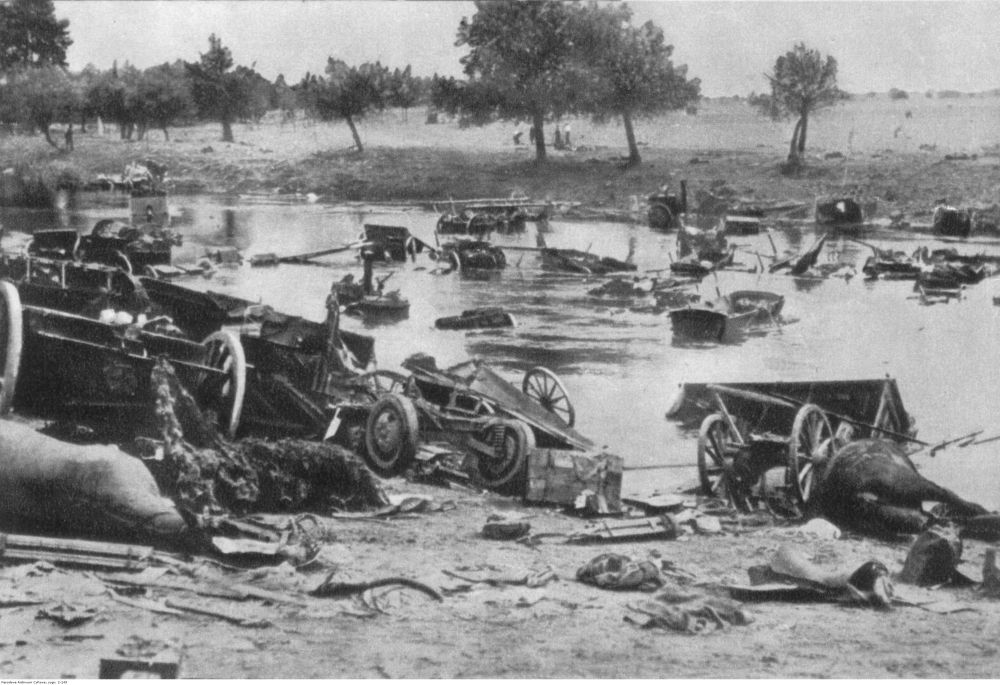 Czarno-biała fotografia pola bitwy. W rzece pływają i nad jej brzegiem leżą zniszczona broń i fragmenty pojazdów. - grafika artykułu
