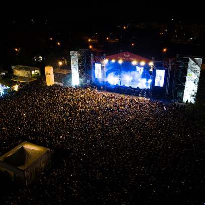 Zdjęcie z powietrza pokazujące tłum publiczności zgromadzony przed sceną oświetloną światłami scenicznymi