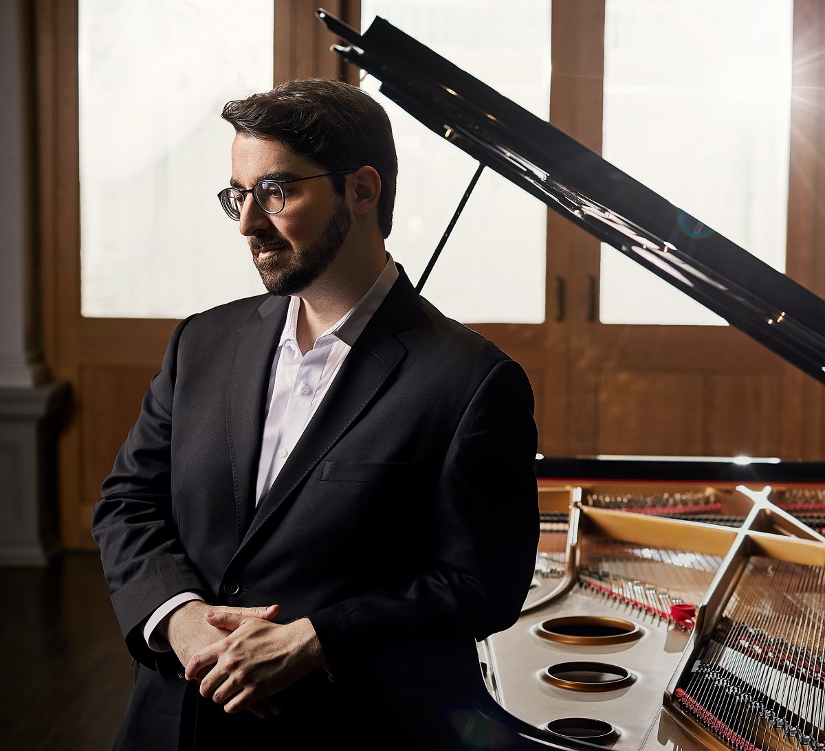 Charles Richard-Hamelin, photograph: Julien Faugere A man in a shirt and jacket stands at the grand piano.