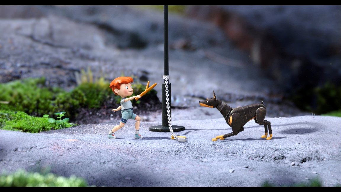 Animated picture from the movie - a boy holding a stick and standing against a dog; a chain between them.