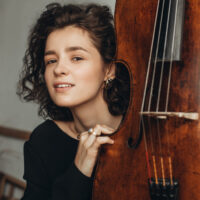 A photo of the artist - a young woman by a cello