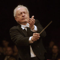 Photo of the conductor - a man with a conductor's baton in his hand on a black background