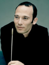 Photo of the conductor - a man in black clothes with conductor's baton