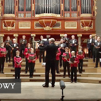Members of the choir standing in front of pipe organ