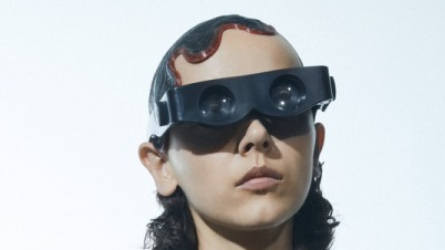 A picture of the artist - a young woman striking a pose, in dark garment and 3D glasses