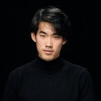 Photo of the pianist - a man in black clothes on a black background