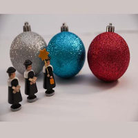 Picture of three Christmas balls (silver, blue and red) and three small figures of carollers.