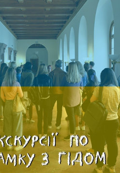 Photo of group of people in a corridor, listening to a young woman. Blue and yellow colours.