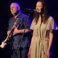 Photo of the performers: young woman singing to a microphone and a man holding a trumpet in his hands.