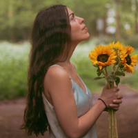 Photo of the artist holding sunflowers in her hands.