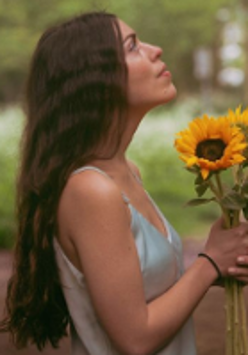 Photo of the artist holding sunflowers in her hands.