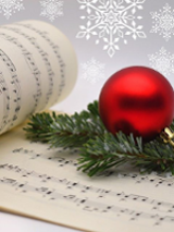 Photo of music notes and a christmas ball on a spruce branch.