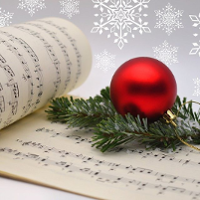 Photo of music notes and a christmas ball on a spruce branch.