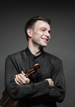 Photo of the artist, Amihai GROSZ, who is holding the violin in his hand