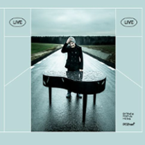 Photo of a man standing behind the grand-piano on the empty asphalt road.