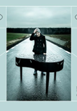 Photo of a man standing behind the grand-piano on the empty asphalt road.