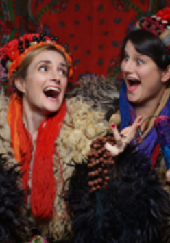 Photo of two laughing young women in folk costumes.