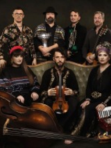 Photo of the band: seven people, three of them sitting on a sofa.