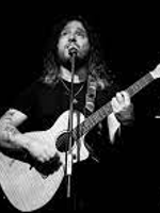 Black and white photo of Gabriel Agudo singing to the microphone and playing the guitar.