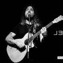Black and white photo of Gabriel Agudo singing to the microphone and playing the guitar.