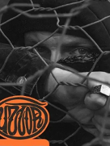 Black and white photo of a partly covered man's face behind mesh fence