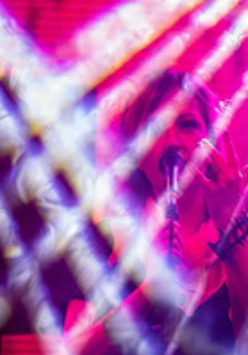 PIcture of a singing woman; picture in dark pink and violet colours.