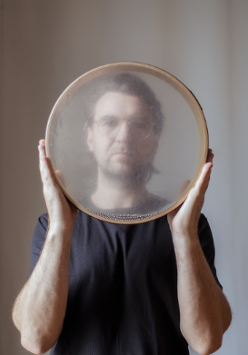 Picture of Krzysztof Dysa - a man holding a round object tat looks like a tambourine in front of him.