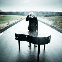 Photo of the artist - a young man standing by the piano on the road.