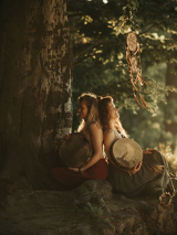 Two women sitting under the tree, back to back.