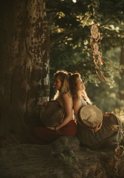 Two women sitting under the tree, back to back.