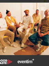 Photo of the band - five men sitting on chairs.