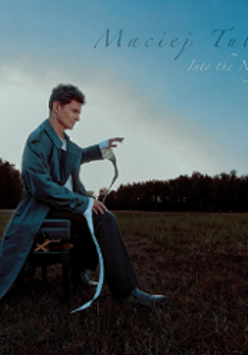 Phto of Maciej Tubis, sitting on a chair on a field, trees as a background.