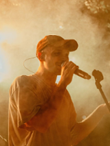 Photo of a young man singing to a microphone.