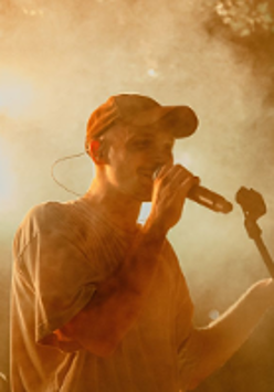 Photo of a young man singing to a microphone.