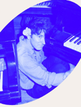 Photo of Marcin Masecki sitting at the piano. Picture in blue colours.