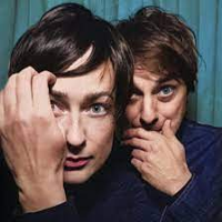 Photo of a woman and a man's faces, which are close to each other. A man and a woman touch their faces with their hands.