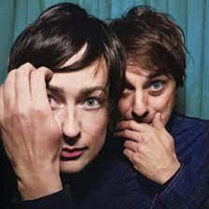 Photo of a woman and a man's faces, which are close to each other. A man and a woman touch their faces with their hands.