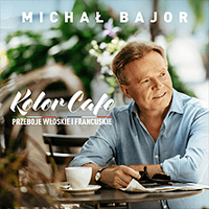 Concert poster - photo of Michał Bajor sitting at the table with a cup of coffee on it.