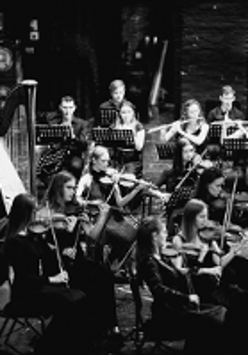 Black and white photo of the orchestra performing on stage.