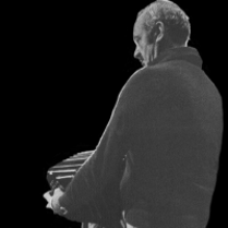 Gray silhouette of a man playing the accordion; black background.