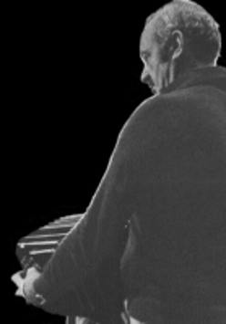 Gray silhouette of a man playing the accordion; black background.