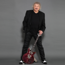 Photo of Piotr Kuźniak standing with a guitar