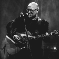 Black and white photo of the artist - Robert Kasprzycki playing the guitar
