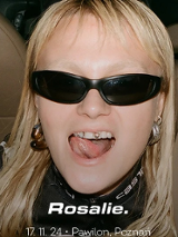 Photo of a young woman in black sunglasses; she has her mouth open and shows her tongue.
