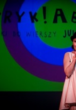 Photo from the concert: a woman singing to a microphone, blue and green background.