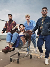 Photo of the band - four young man, one of them is sitting in a shopping trolley.