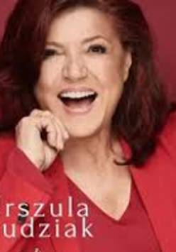 Photo of smiling Urszula Dudziak in red clothes on red background.